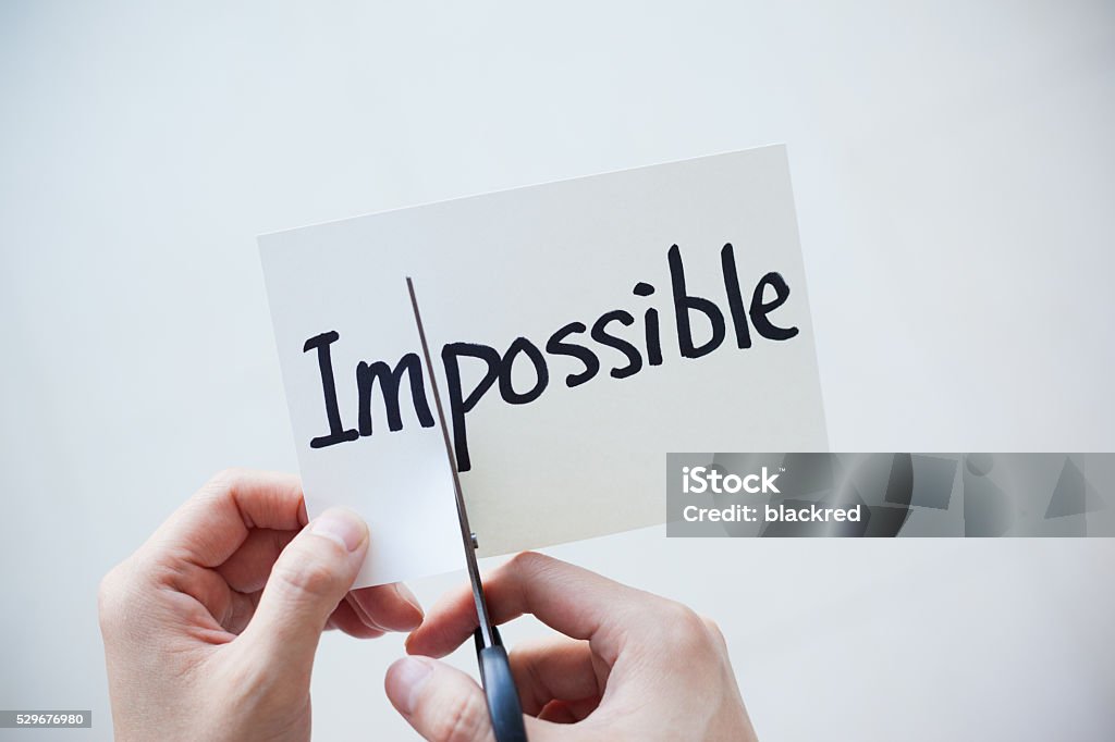 Using Scissors Cut the Word on Paper Impossible Become Possible Close-up of hand using scissors cutting the word on paper, Impossible become Possible. Attitude Stock Photo