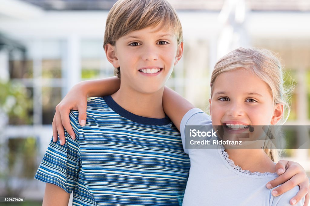 Brother and sister embracing Cheerful young brother and sister embracing each other. Cute children smiling and looking at camera. Portrait of happy young boy and little girl hugging. Family with Two Children Stock Photo