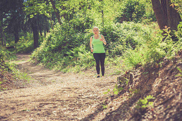 istock Young blonde woman running outdoors in the forest 529682390