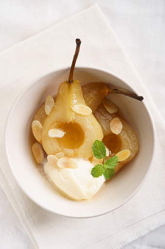 sweet poached pear cut half with vanilla ice cream