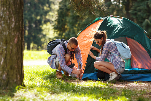 Couple camping. Young people setting up the tent.