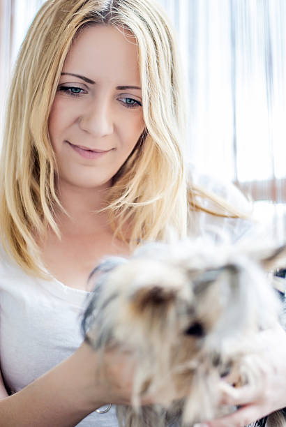 Portrait of attractive young woman sitting behind the window, while playing with little dog