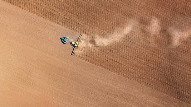 Farm tractor planting and cultivating spring fields, aerial view Farm tractor planting and cultivating spring fields, aerial view. overcasting stock pictures, royalty-free photos & images