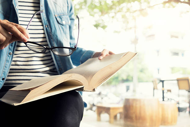 utilisez des lunettes pour femme lisant un livre dans la bibliothèque, café. - medical exam science research scientific experiment photos et images de collection