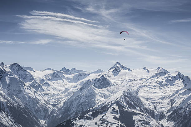 yellow paraglider in blue sky above mountain
