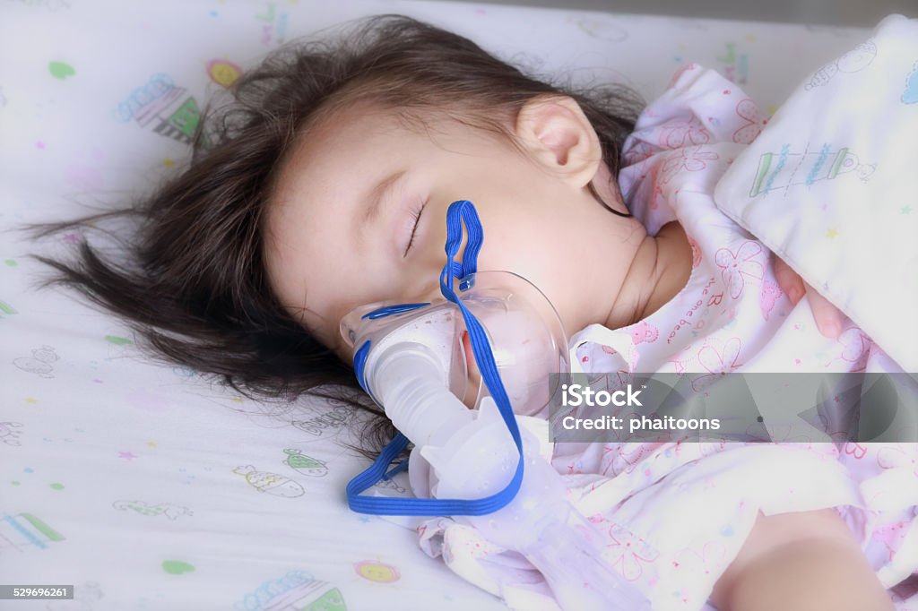 baby girl with a mask for inhaler in hospital. Baby - Human Age Stock Photo