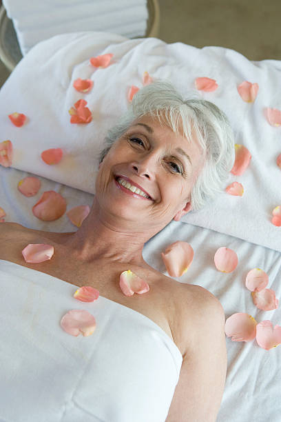 istock Senior woman covered in petals on bed 529723403