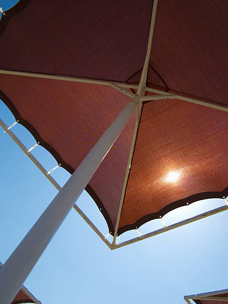 istock Red metallic parasol beach umbrella over blue sky 529724167