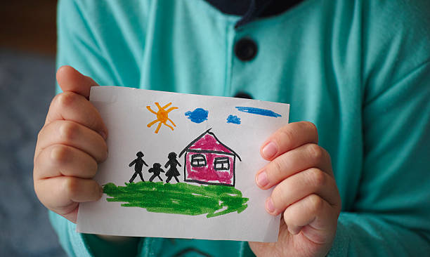 istock Child holds a drawn house with family 529725463
