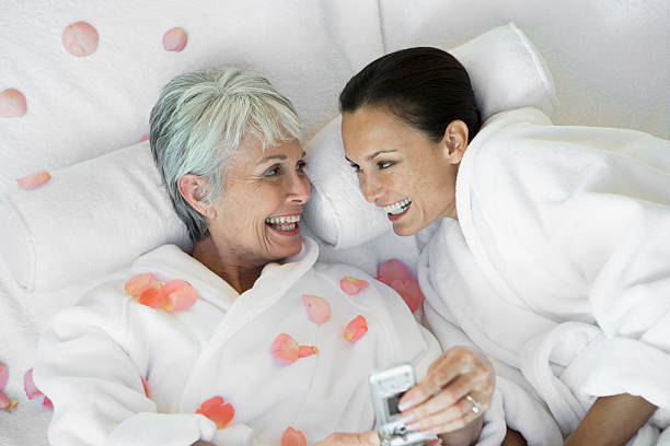 Mother and daughter with mobile phone on bed