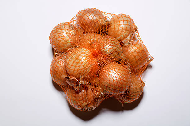 cebolas em uma rede, elevação vista - onion bag netting vegetable imagens e fotografias de stock
