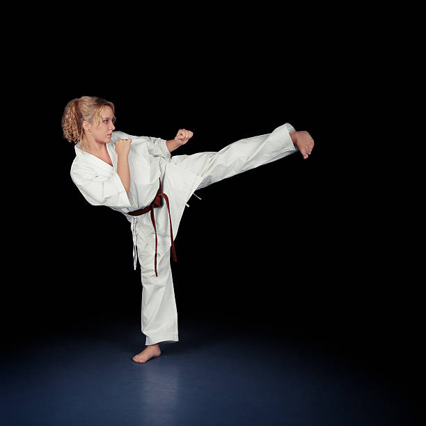 istock Young Karate Woman in a White Kimono Kicking 529746535