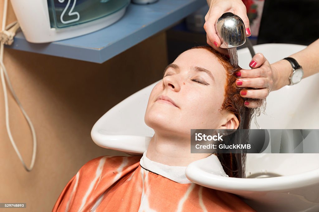 Hairdresser washes the paint from the client's head with water Hairdresser washes the paint from the client's head with water in salon Adult Stock Photo