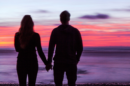 couple holding hands on beach at sunset