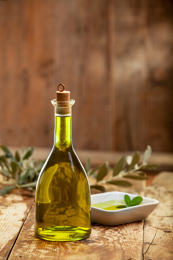 Extra virgin healthy olive oil with vegetable on rustic wooden background.