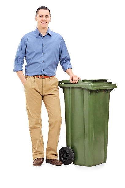 istock Young man standing by a large green trash can 529770755