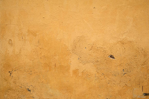 istock Texture of old wall covered with yellow stucco 529785491