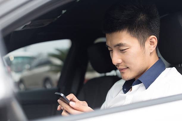 istock asian young businessman using smartphone in car 529790657