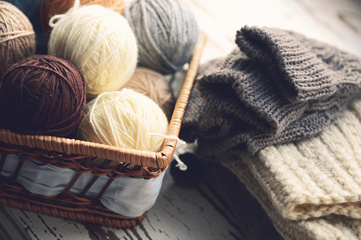 balls of wool in a basket on a wooden background