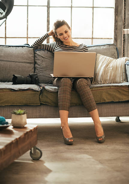 istock Happy young woman with dslr photo camera using laptop 529873225