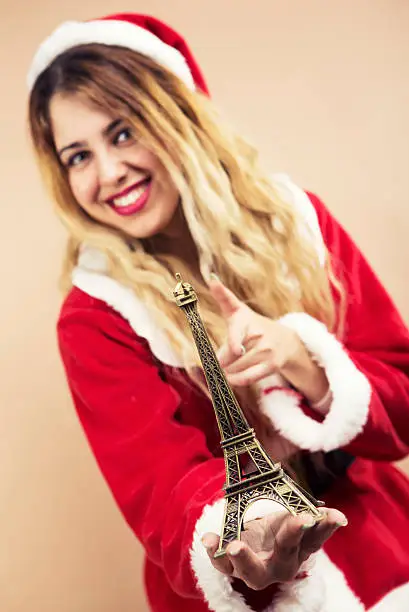 Happy Mrs.Claus holding eiffel tower souvenir and smiling