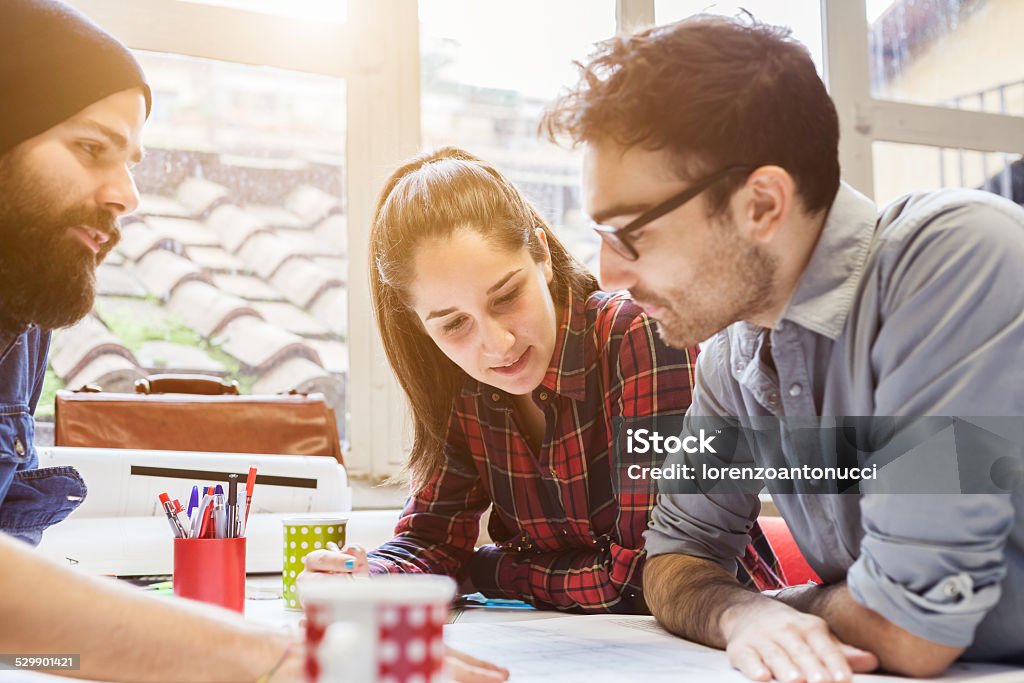 Lavoro di squadra. Tre giovani architetti che lavorano su un progetto - Foto stock royalty-free di Adulto