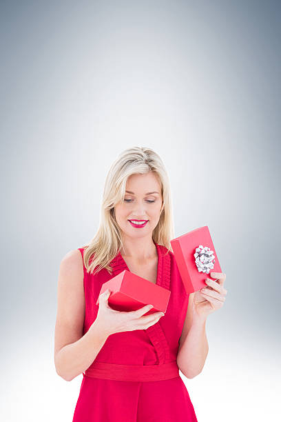 istock Stylish blonde in red dress opening gift box 529901889