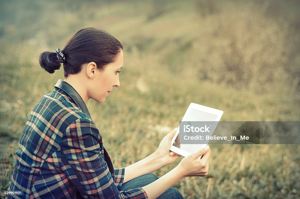 Young woman using tablet outdoor Young woman using tablet outdoor sitting on grass  Adult Stock Photo