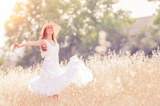 young woman with open arms in the field, selective focus, vintage color editing and noise added