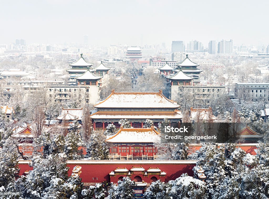 Beijing Winter Cityscape Snow over the skyline of Beijing, looking north, with the trees and buildings of Jingshan Park in the foreground, the Drum Tower (Gǔlóu) in the distant centre of the image, and modern commercial towers beyond. Beijing Stock Photo