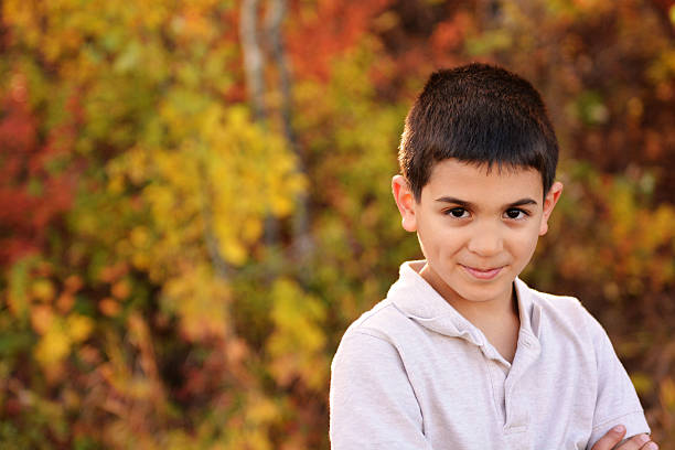 A pensive teenage boy looks at the camera and smiles.
