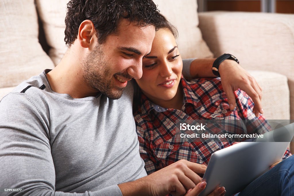 Junge Paar sitzt im Wohnzimmer und über tablet - Lizenzfrei Berührungsbildschirm Stock-Foto