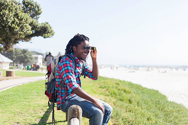 istock Tourist smiling while looking at the ocean through his binoculars 529952911