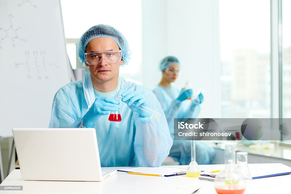 Serious chemist Confident clinician studying new substance in laboratory and looking at camera Adult Stock Photo