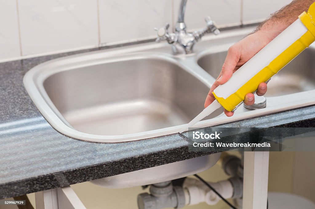 Plumber putting filling in between tiles Plumber putting filling in between tiles in the kitchen Arranging Stock Photo