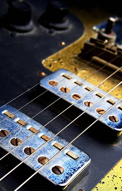 Close up of the pick ups and the strings of an old electric guitar