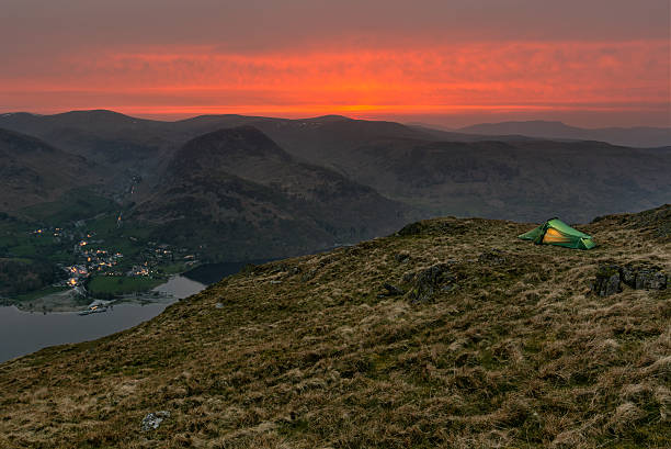 istock Green glowing backpacker tent on mountain with orange sunset. 529978226