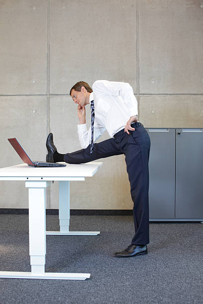 istock business man stretching in standing position at desk leg 529981551