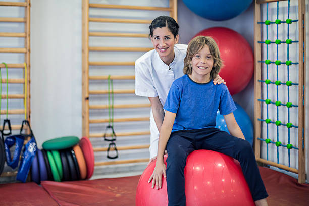 Portrait of nurse and child doing rehabilitation Portrait of nurse and boy doing  rehabilitation exercises with large ball in the hospital. ass boy stock pictures, royalty-free photos & images