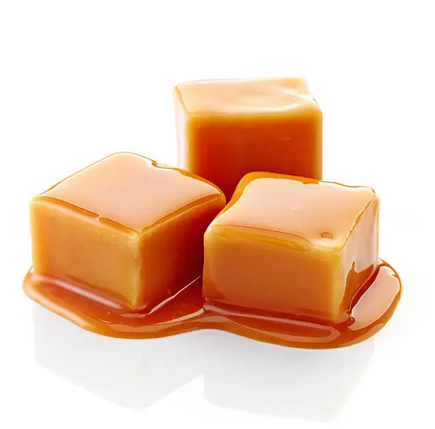 caramel candies and caramel sauce on a white background