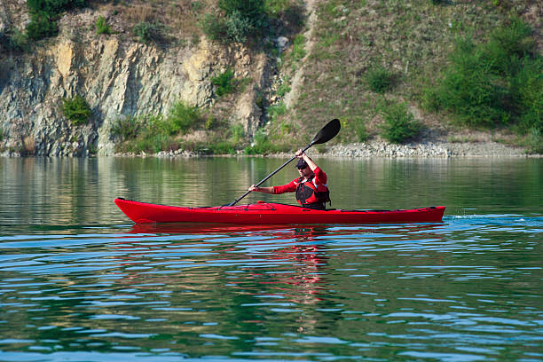 человек на красную каяке возле берег - rowboat river lake nautical vessel стоковые фото и изображения