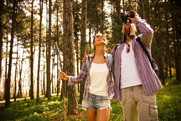 Couple hiking. Couple hiking trough forest on beautiful summer day.Watching birds. bird watching stock pictures, royalty-free photos & images