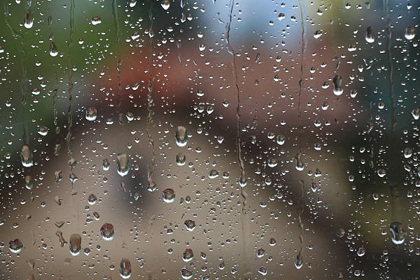 istock Rain drops on window with house and church in background 529985740