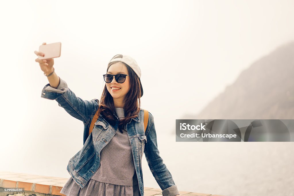 Asian traveler taking selfie with ocean view, soft warm tone Beautiful Asian traveler taking selfie with ocean view background, soft warm light tone Chinese Culture Stock Photo