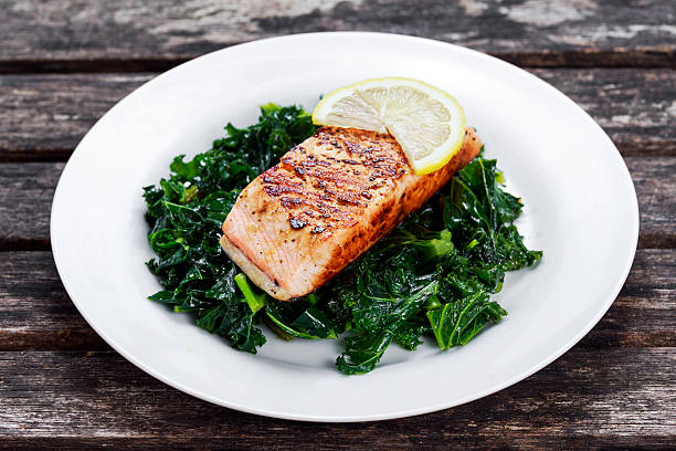 Pan fried Salmon Served with Kale on plate Pan fried Salmon Served with Kale on plate. sockeye salmon filet stock pictures, royalty-free photos & images