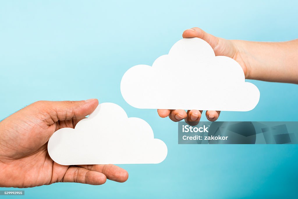 Two hands holding white empty clouds. Cloud computing storage concept Two hands showing two paper white blank clouds on blue background. Cloud computing or storage online concept. Cloud Computing Stock Photo