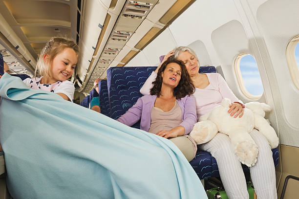 istock Women sleeping and girl pulling blanket  on airplane 529994781