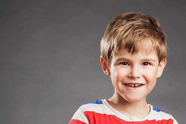 istock Mischieveous young boy lookign at camera against gray background, portrait 529994789