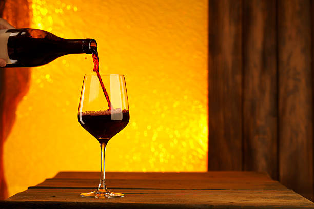 istock Pouring red wine from an elegant bottle into stylish wineglass 529994995