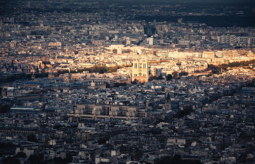 Paris cityscape with Notre Dame cathedral illuminated by the sunset light.